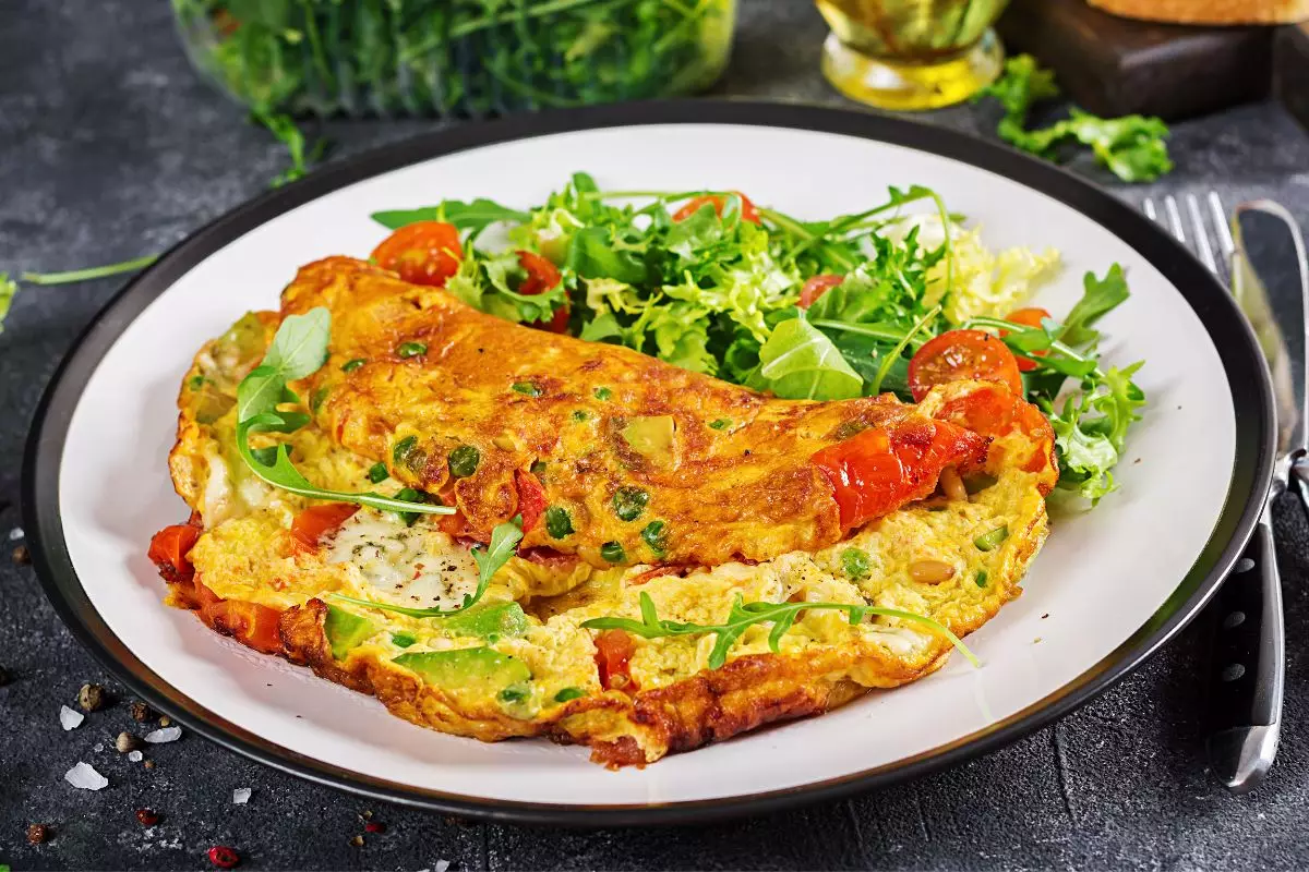 Omelete de vegetais com torradas integrais e salada de frutas